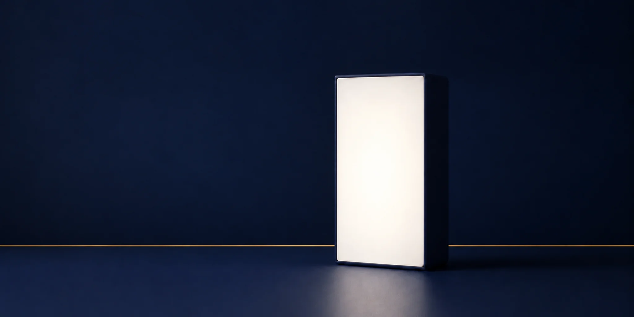 Rectangular light therapy box with a matte navy housing glowing in a navy room, with a thin gold line along the floor seam.